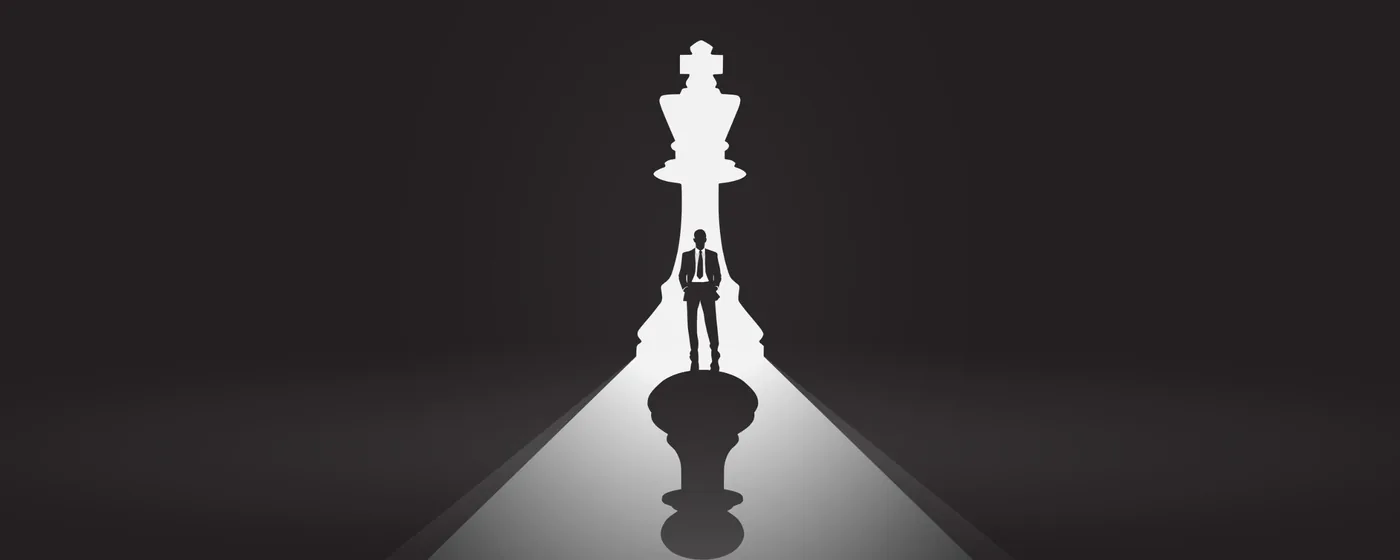 The silhouette of a leader standing inside the shadow of a towering chess king