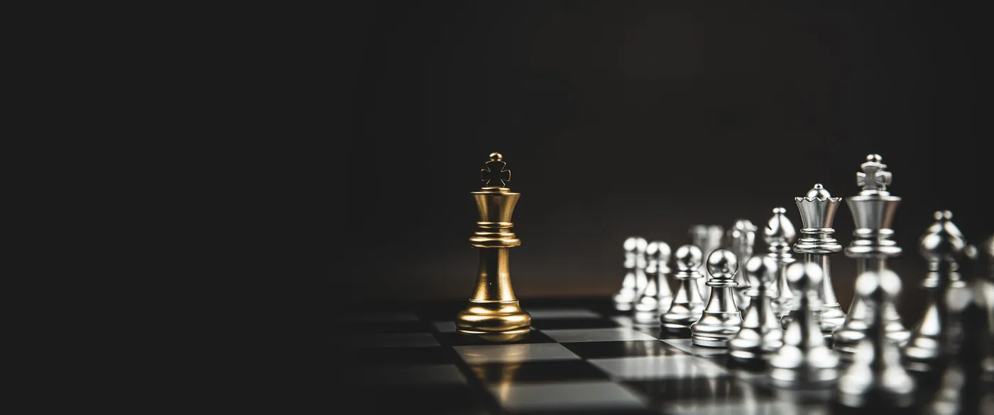A gold king chess piece stands apart from rows of silver pieces